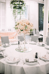 Restaurant, banquet, table setting. The table is covered with a white tablecloth, dishes, white clean plates, cutlery, napkins, wine glasses, candles. Close-up.