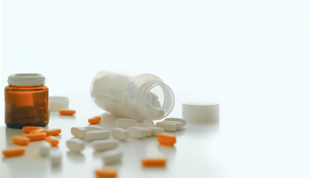 Pills spilling out of a pill bottle on white. with copy space. Medicine concept.