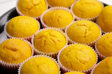 Muffins on black ceramic plate, selective focus. Group of yellow color pumpkin cupcakes