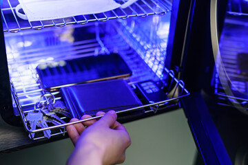 UV light sterilization of mobile phone and face mask to disinfection. COVID-19 prevention concept. ultra-violet sterilization and disinfection.