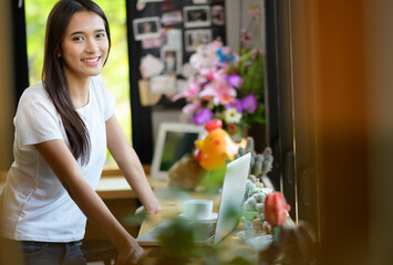 Asian woman or a happy student smiles on a desk with a computer.