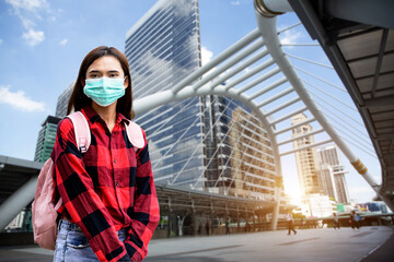 Obraz premium The woman wearing a mask is in a town where people walk around.covid 19