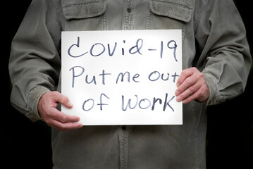 Unemployed man holding handmade sign covid-19 put me out of work