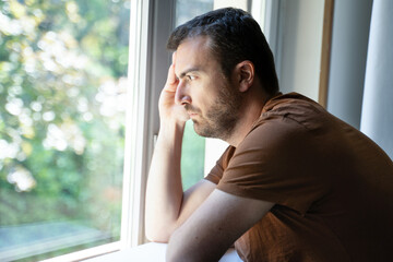 Fototapeta na wymiar Portrait of one guy feeling sad and looking through window