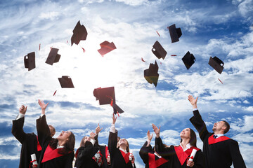 Happy students with diplomas throwing graduation hats in air outdoors