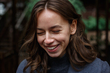 closeup on young smiling happy pretty girl in gray coat and turtleneck posing outdoors. Street style portrait photo session of attractive female, urban photoshoot of beautiful elegant model, close up