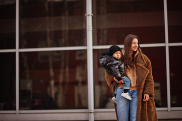 Young mother with child on hands walking down streets.
