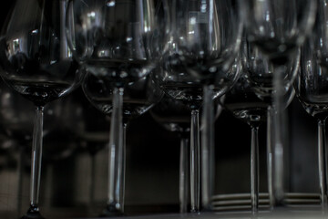 Wine glasses standing on a shelf and waiting to be served. Room is dark but glasses reflects the lights.