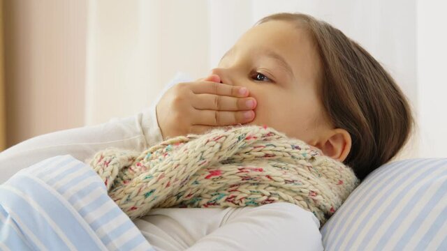 health, children and people concept - sick coughing girl lying in bed at home