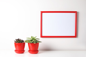 Red and white frame poster with plant in pot on table.