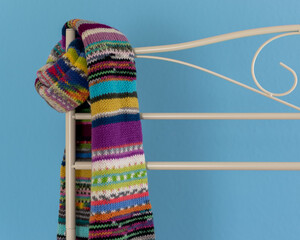 colourful hand knit scarf on boutique stand with blue background 