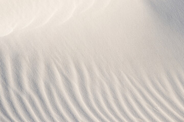 Light patterns on the sand of dune. Sand texture. Sandy beach for the background. Top view. Background, sand, light, beige, wave, reflect, shadow, summer.