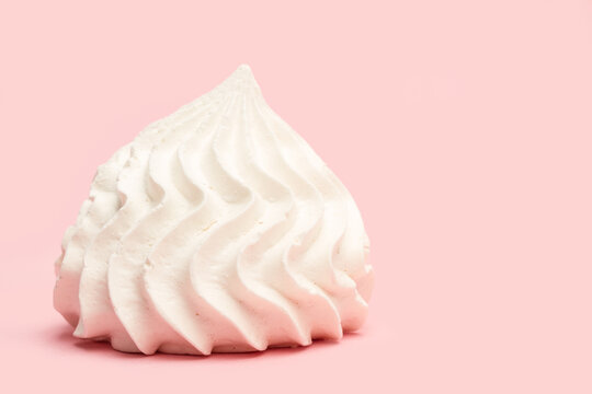 Un malvavisco merengue blanco en primer plano sobre un fondo rosa liso y aislado. Vista de frente. Copy space