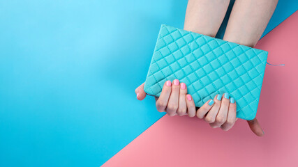 Women's hands with pink and blue nail polish on a bright copybook. Concept of a fun manicure and summer mood