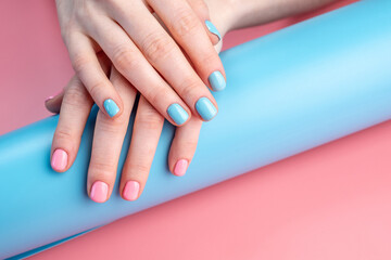 Women's hands with bright summer manicure on a blue and pink background. Trendy glamorous nails in fun colors