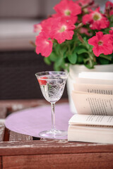 Beautiful composition with glass of water with old book and flower  on table close up