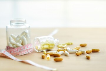 White slimming pills in glass bottles and measure And yellow pill capsules in falling glass bottles And drugs distributed on the floor, the concept of weight loss and weight loss drugs