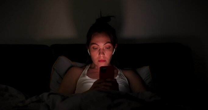 Woman before falling asleep hangs in the smartphone at home in bed