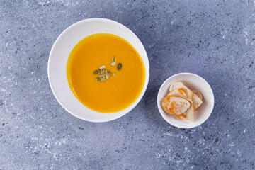 pumpkin soup in a plate on a gray background