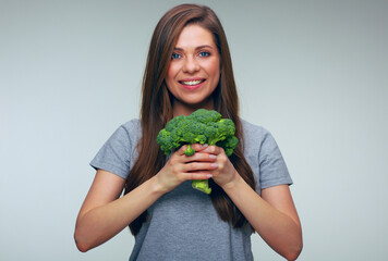 Woman holding big broccoli in front of her self.