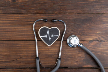 Workplace of a doctor. Stethoscope and little heart on wooden desk background