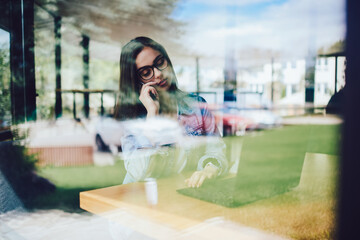 Attractive copywriter in eyeglasses communicating via smartphone