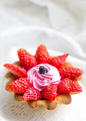 Obraz na płótnie Canvas beautiful tasty cupcake close up with strawberries, honeysuckle and pink cream