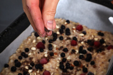Girl fingers put ingredients on vegetarian sweet fruit pizza with berries. Fresh pizza in a casserole at home kitchen. Vegetarian food concept. Close up, selective focus