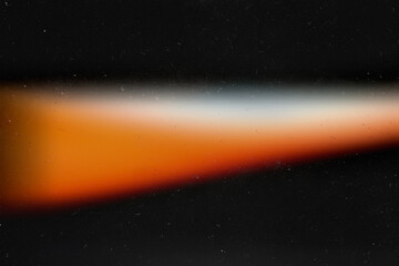 Light orange effect on black background. Abstract wallpaper. Analog film texture