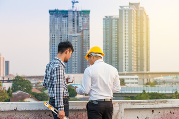Engineer and worker using tablet for consulting about project at construction site and cityscape background.