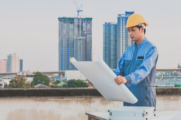 Worker with helmet looking paper plans at construction site.