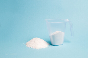 measuring cup with detergent on a blue background copy space, laundry concept