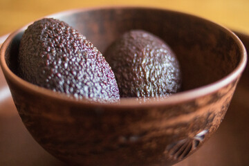 Fresh green tasty avocado lies in clay natural dishes on a wooden oak table