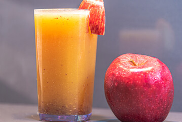 Glass of fresh apple juice and fruit on dark background...