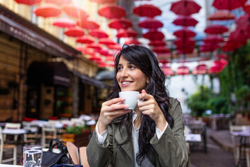 Beautiful young woman with cup of coffee. Woman enjoys fresh coffee in the morning with sunrise at coffe shop Beautiful woman drinking coffee in the morning sitting outdoors