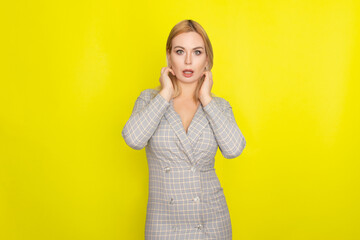 Attractive blonde woman in plaid jacket dress over yellow background