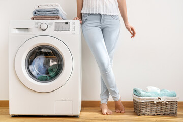 Young woman washing with washing machine
