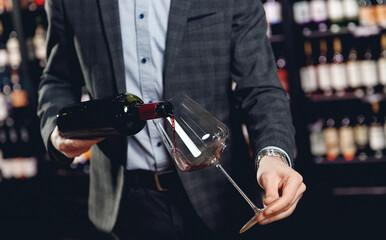 Sommelier pouring red wine into long-stemmed glasses