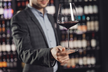 Waiter serves glass of red wine in restaurant, dark background