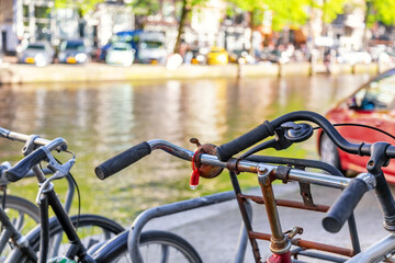 Fototapeta na wymiar Bicycles parking lot in Amsterdam, Netherlands against a canal during summer sunny day. Amsterdam postcard iconic view. Tourism concept.