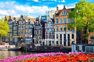 Cityscape view of the canal of Amsterdam in summer with a blue sky, houseboat and traditional old...
