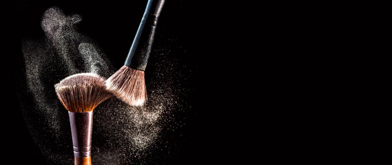 Make up cosmetic brushes with powder blush explosion on black background. Skin care or fashion concept. Free space for your text