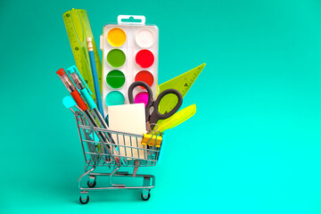 School stationery in a toy shopping cart on a green background