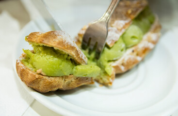 Top view close up of pistachio eclair, traditional French dessert, over a white plate, Strasbourg, Alsace, France. 