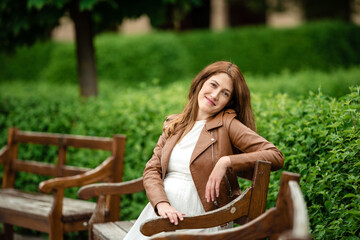 Beautiful pregnant woman sitting in the park on the bench.