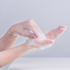 Fototapeta premium Washing hands. Asian young woman using liquid soap to wash hands, concept of hygiene to protective pandemic coronavirus isolated on gray white background, close up.