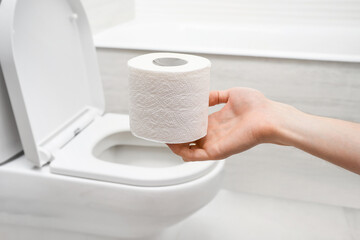 Hand holding toilet paper roll