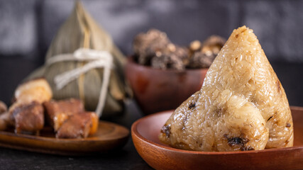 Rice dumpling, zongzi - Chinese rice dumpling zongzi on black brick background slate table, concept of Dragon Boat Festival traditional food, close up.