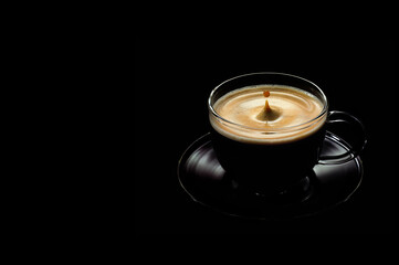 a Cup of coffee with a falling drop on a black background