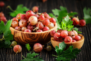 Sweet gooseberries summer harvest in bowl, wooden kitchen table background